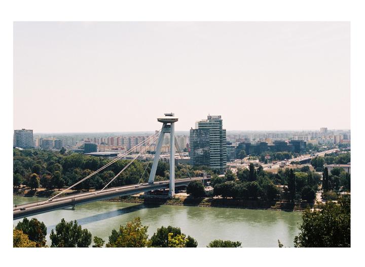 A wide view shows a city with a river and a large bridge with a distinctive tower.