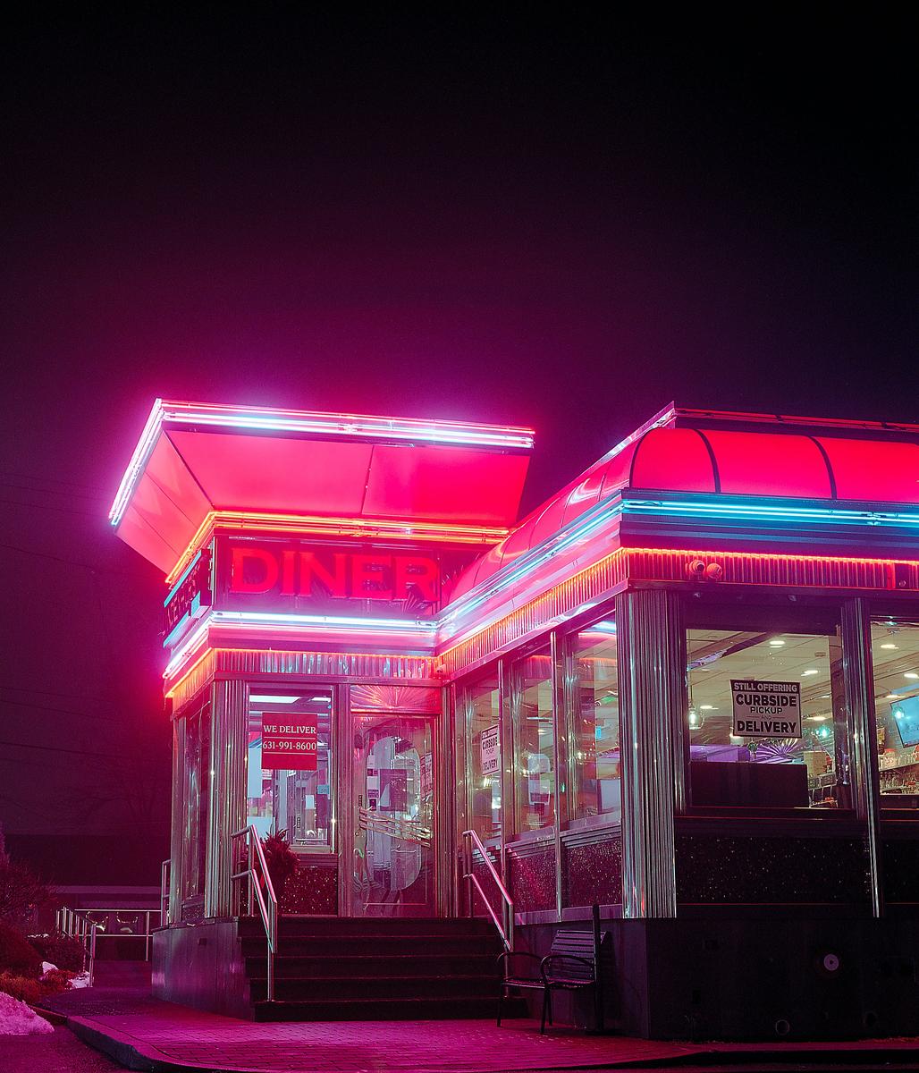 A diner with bright neon lights illuminates the night.