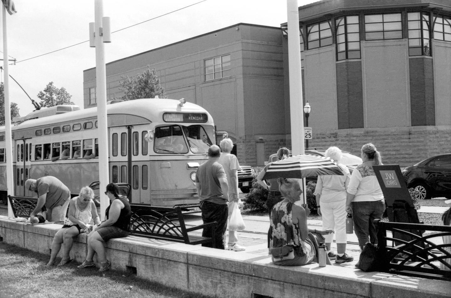 A group of people are gathered on a street next to a trolley car.