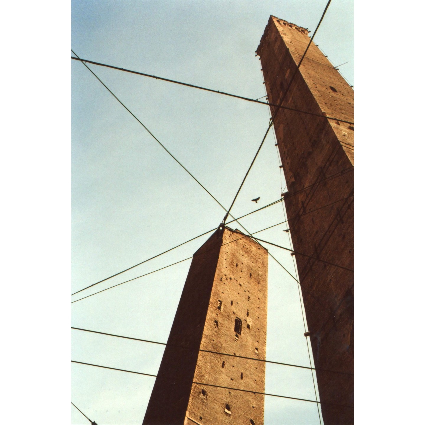 Two tall brick towers are visible against a clear sky, crisscrossed by overhead wires.