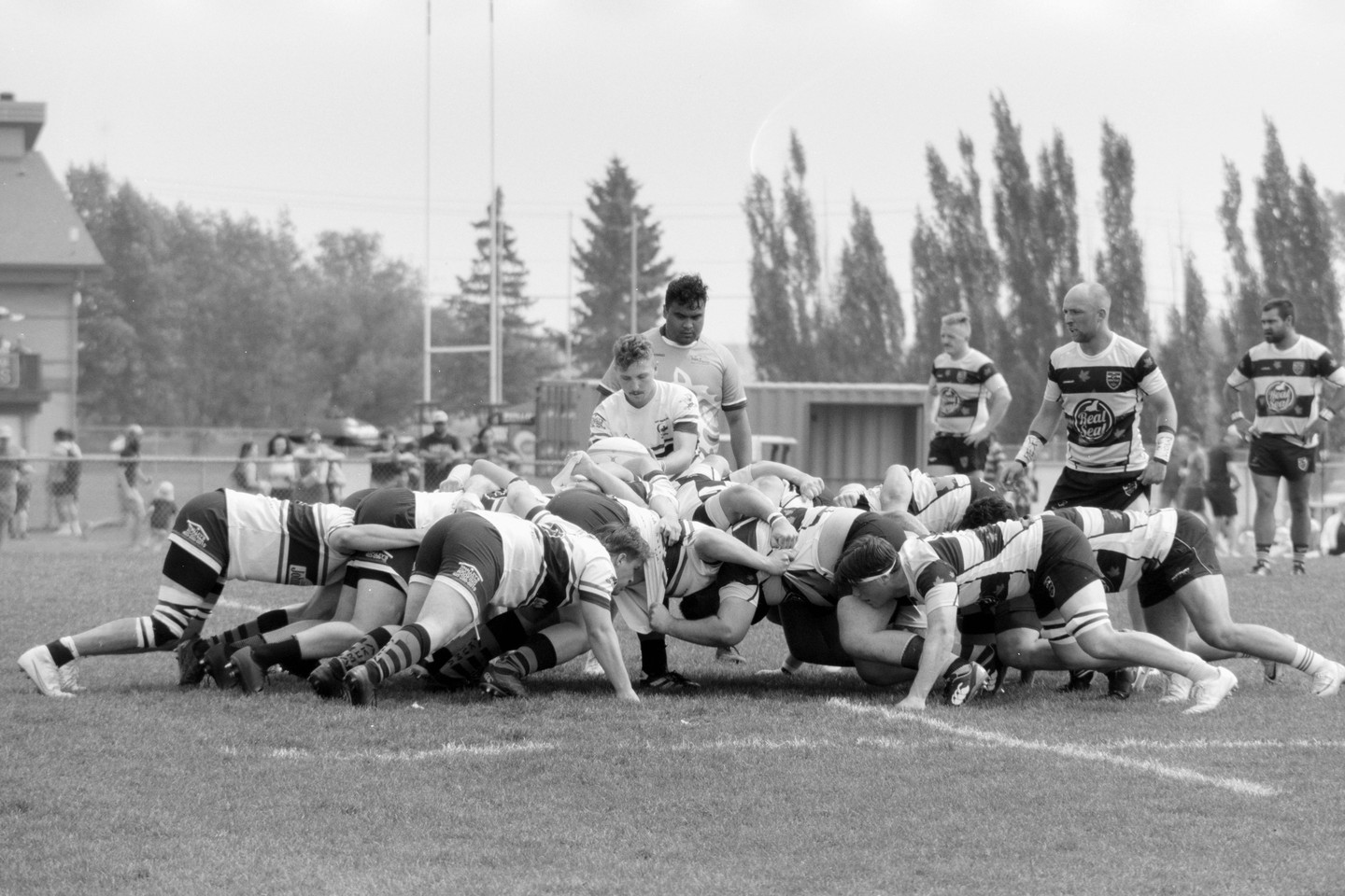 A group of men in uniform are playing rugby on a grassy field.