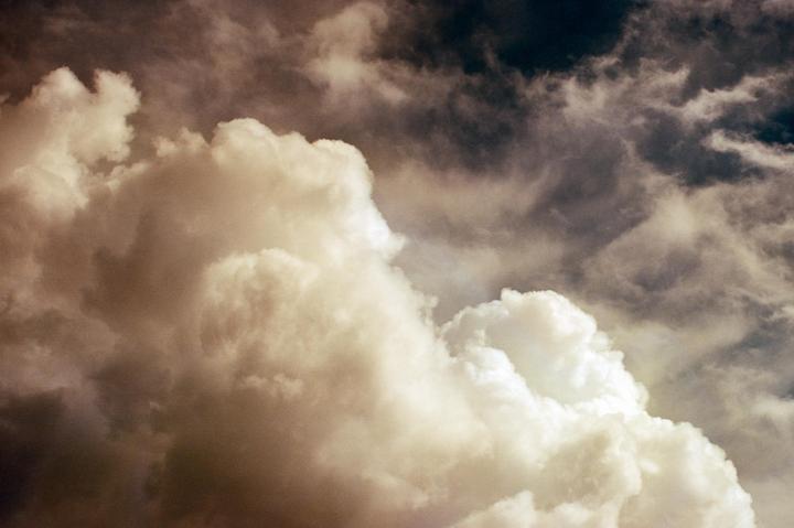 A dramatic sky is filled with large, fluffy clouds and darker, stormy clouds.