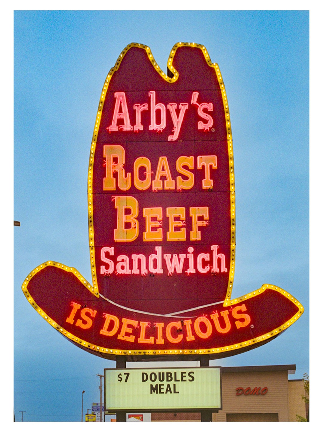 A neon sign shaped like a cowboy hat advertises Arby's roast beef sandwiches.