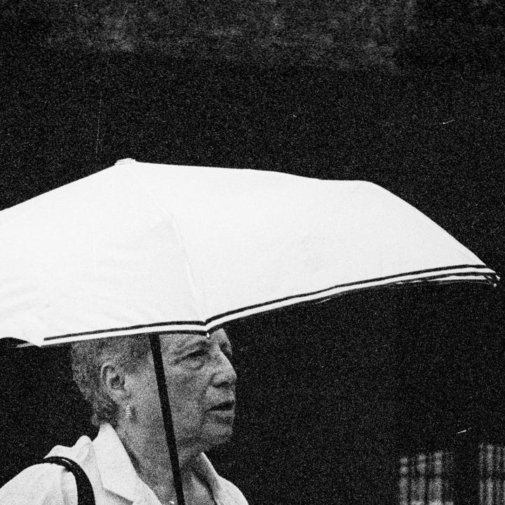 A woman walks with a white umbrella in the rain.