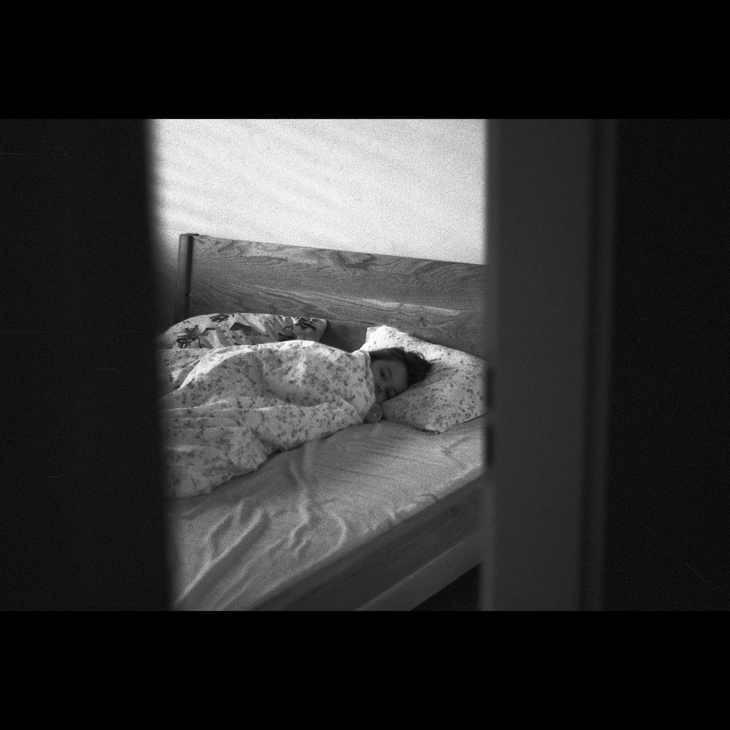 A child sleeps in a bed, partially obscured by a doorway.