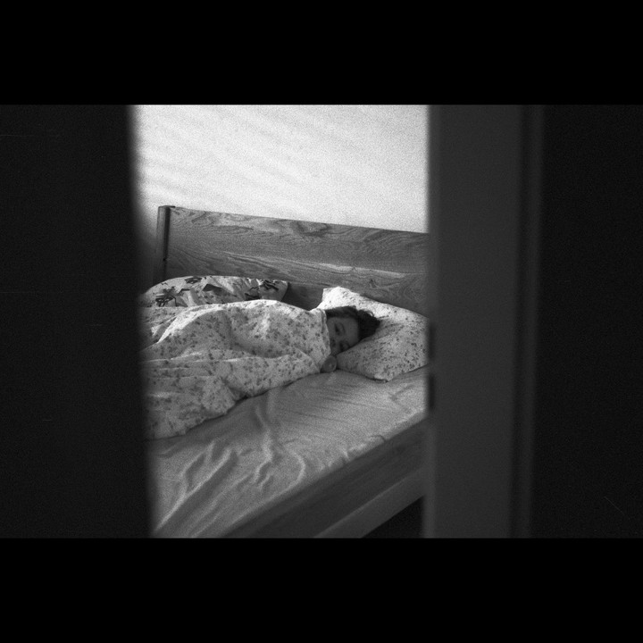 A child sleeps in a bed, partially obscured by a doorway.