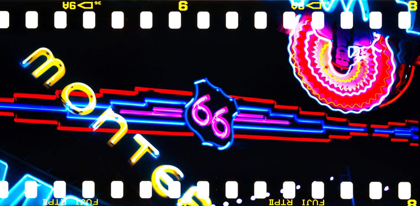 A neon sign for "Route 66" and "Monte" is visible at night, with a colorful spiral neon sign in the upper right.