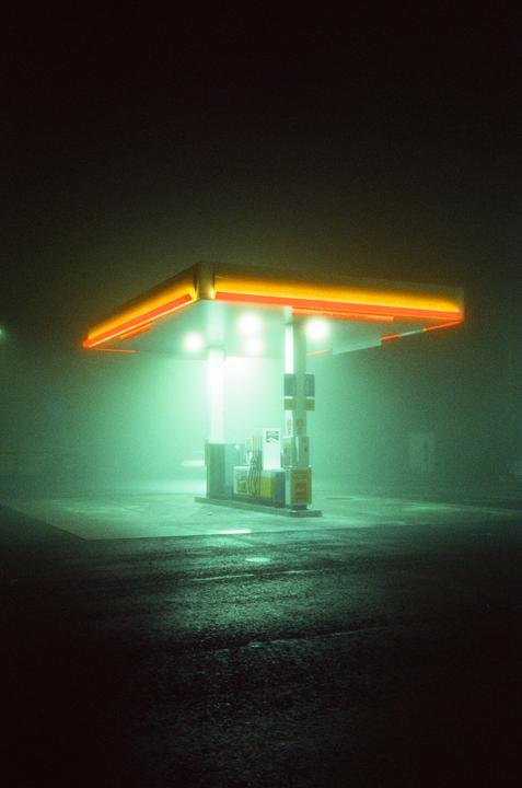 A gas station is illuminated by bright lights on a foggy night.