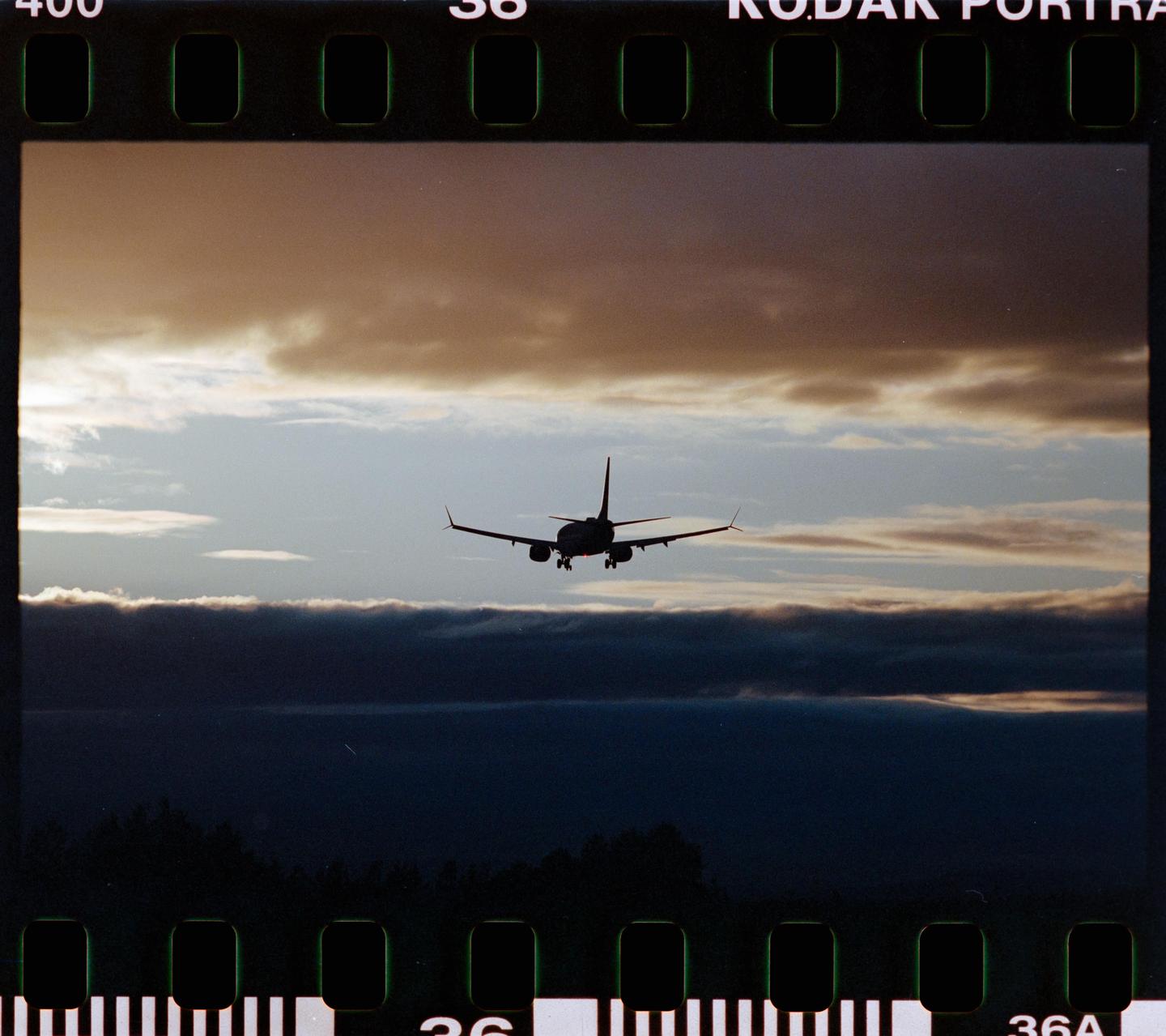 A passenger airplane is silhouetted against a cloudy sky at dusk.