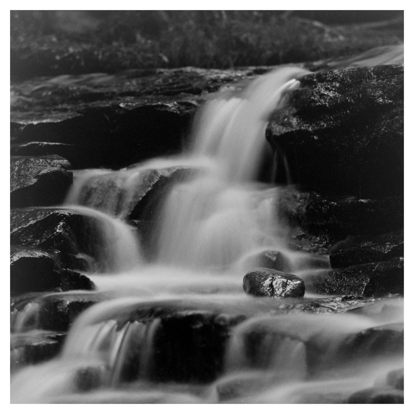 A long exposure captures the smooth flow of water over rocks in a cascading waterfall.