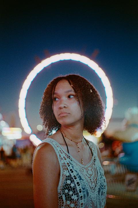 A woman with curly hair looks to the side, with a glowing ring of light behind her head.