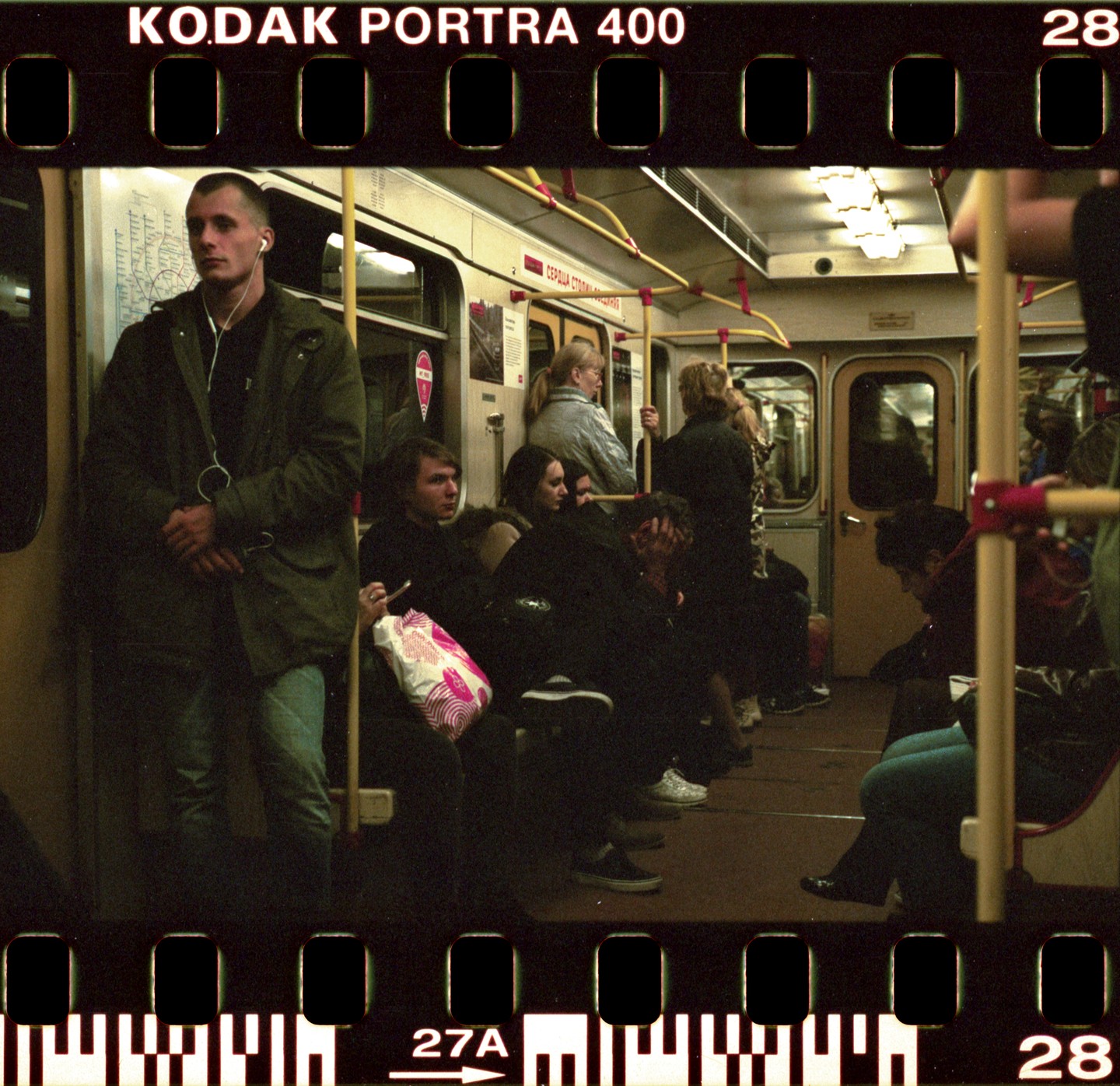 A man stands in a subway car while other passengers sit and stand.