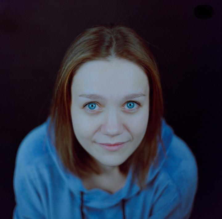 A woman with blue eyes and brown hair looks up at the camera.