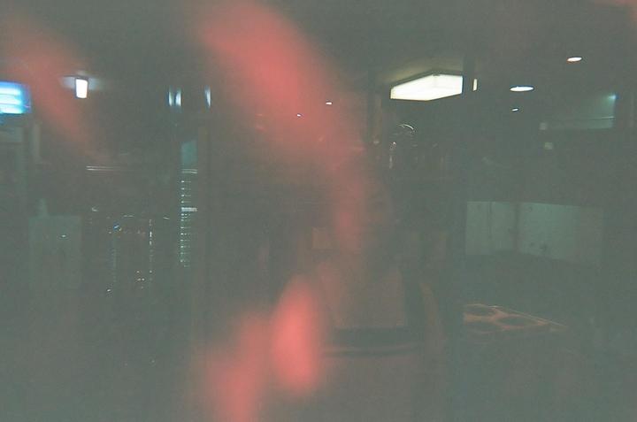 A blurry, dark interior with red light leaks shows a person and a pizza box.