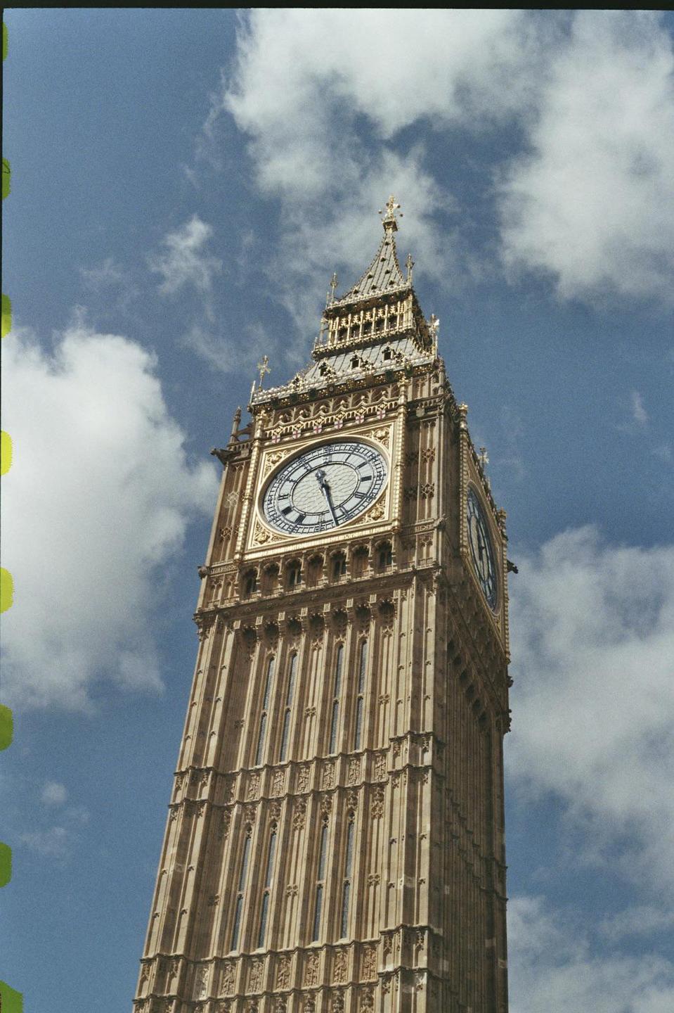 The Big Ben clock tower stands tall against a cloudy blue sky.