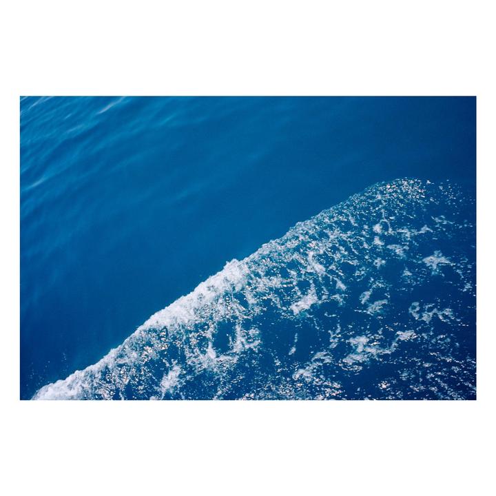 A diagonal line of white foamy water separates two shades of blue water.