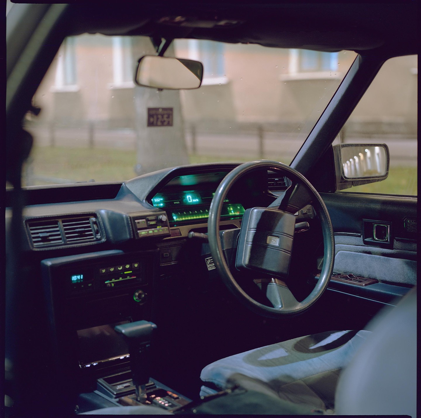 The interior of a car is visible, showing the steering wheel, dashboard, and front passenger seat.