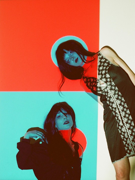 Two women are visible in a split image with red and blue backgrounds and projected circles.