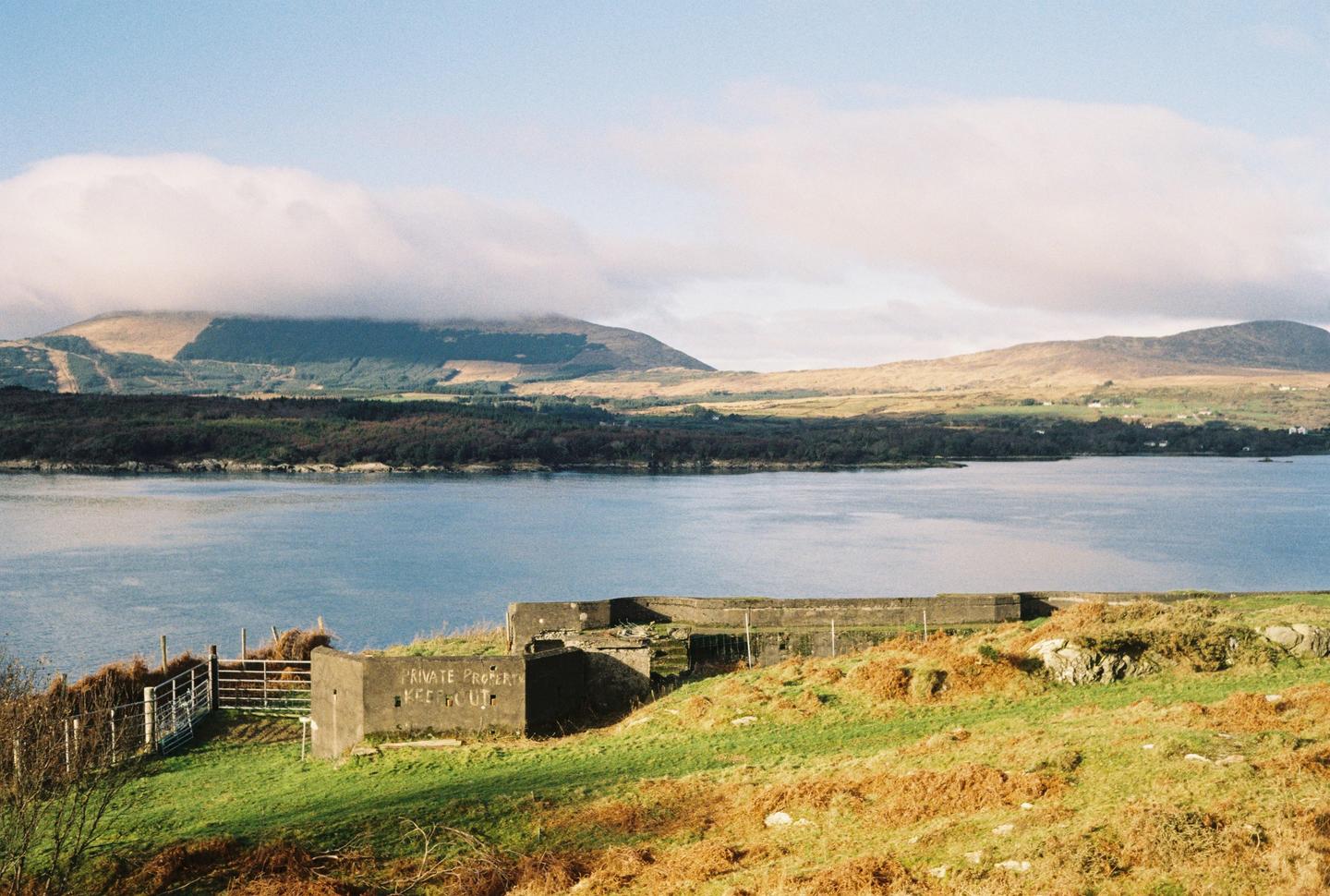 A body of water is visible with mountains in the background and a concrete structure in the foreground.