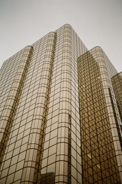 A tall building with golden glass windows reflects the sky.