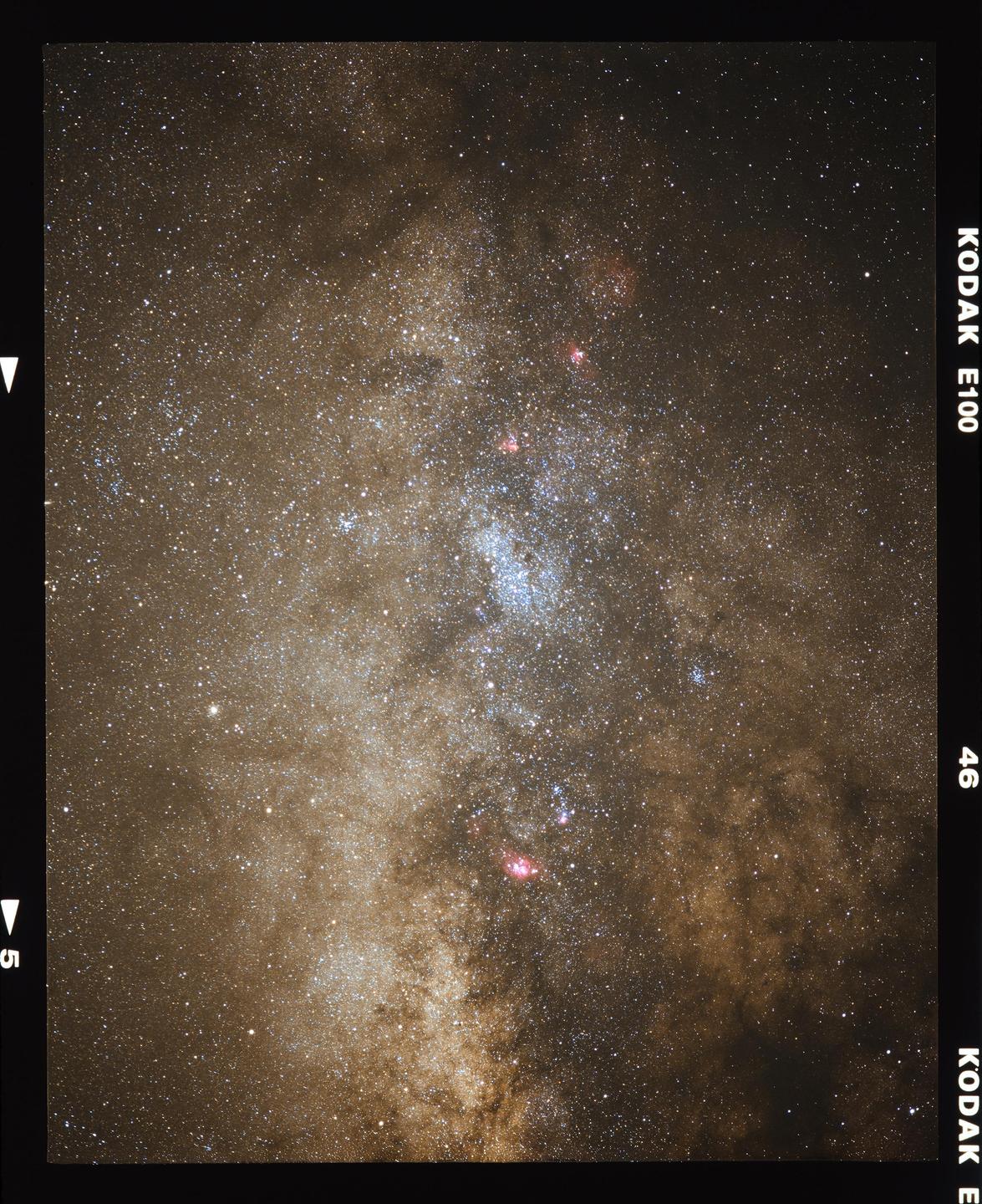 The milky way core is visible in a night sky filled with stars and nebulae.