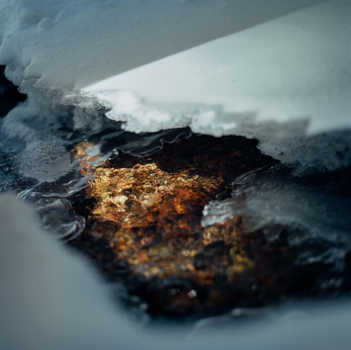 Melted snow runs over rocks and ice.