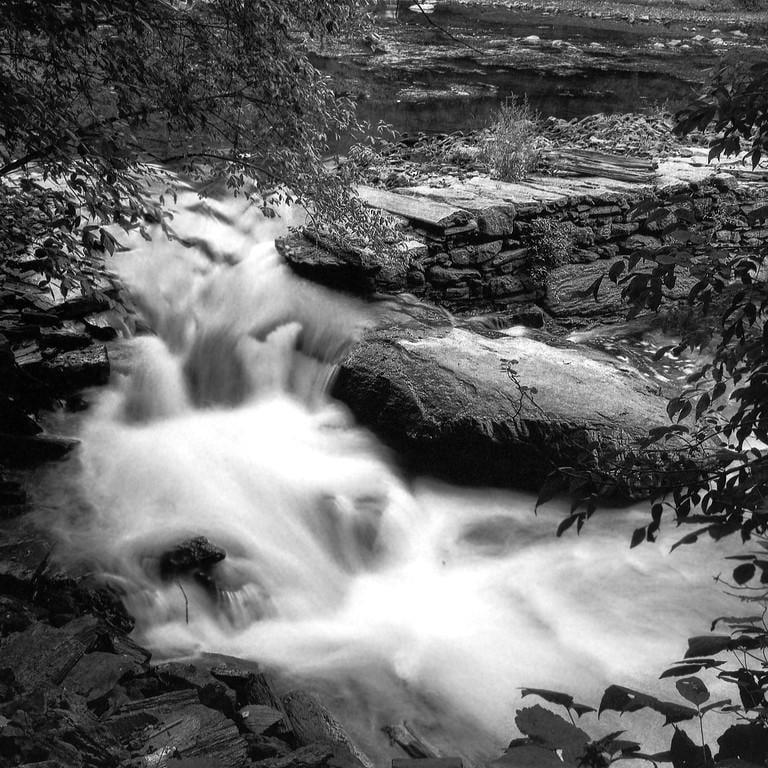 A waterfall cascades over rocks in a forest.