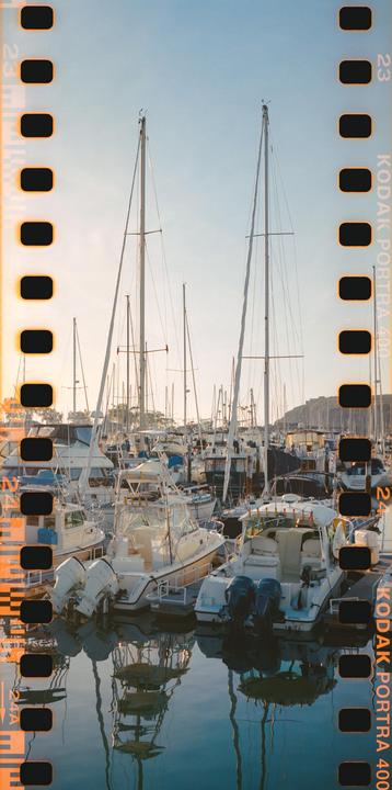 A marina is filled with many boats and sailboats under a bright sky.