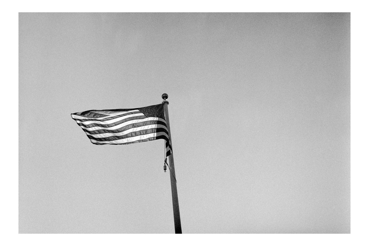 An American flag flies from a flagpole against a clear sky.