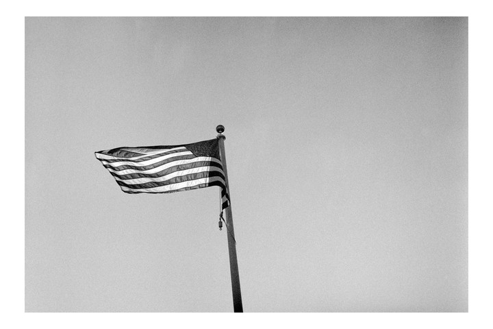 An American flag flies from a flagpole against a clear sky.
