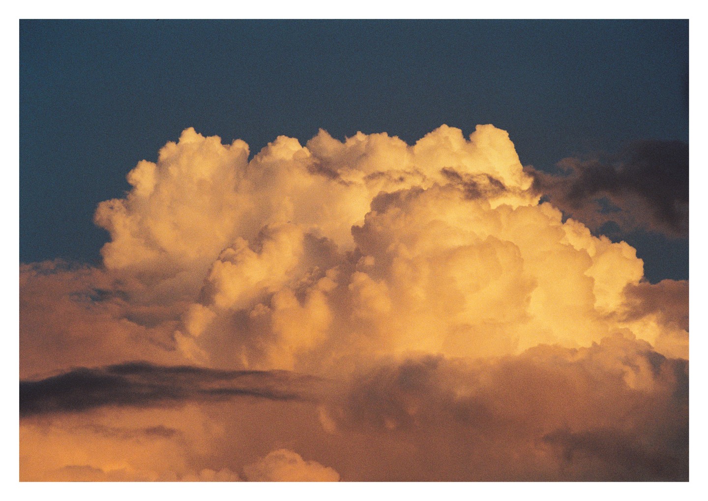 Golden cumulus clouds fill the sky at sunset.