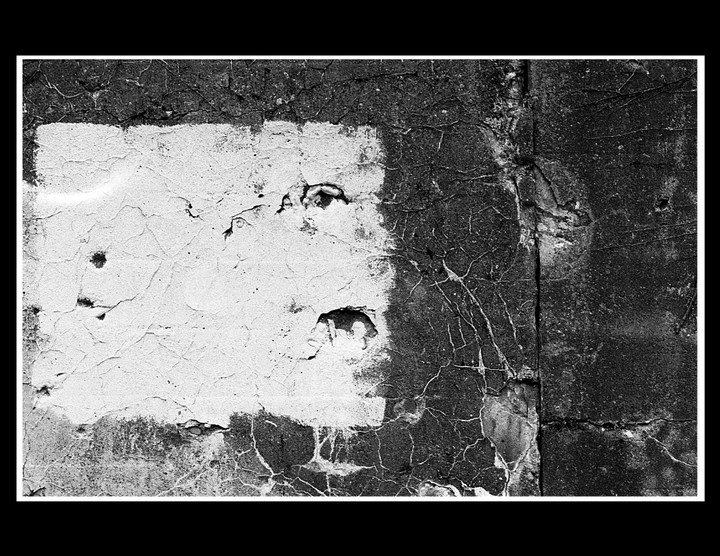 A white rectangle is painted on a cracked, dark wall.