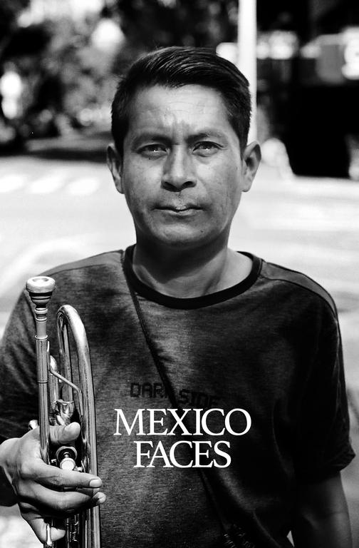 A man holds a trumpet and looks directly at the viewer.