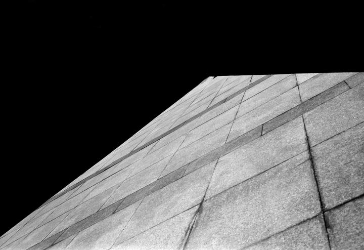 A low-angle view of a tiled building facade is shown against a dark sky.