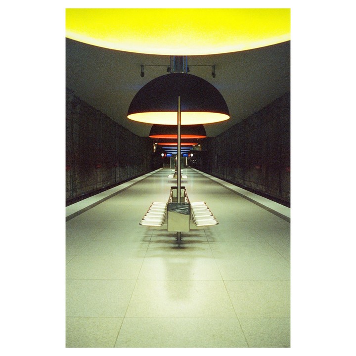 A long, empty subway platform is illuminated by large, circular overhead lights.