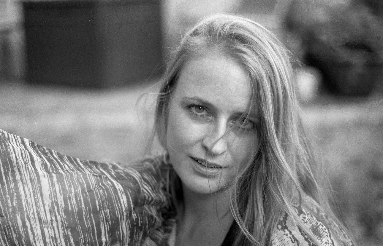 A woman with long hair looks directly at the viewer.
