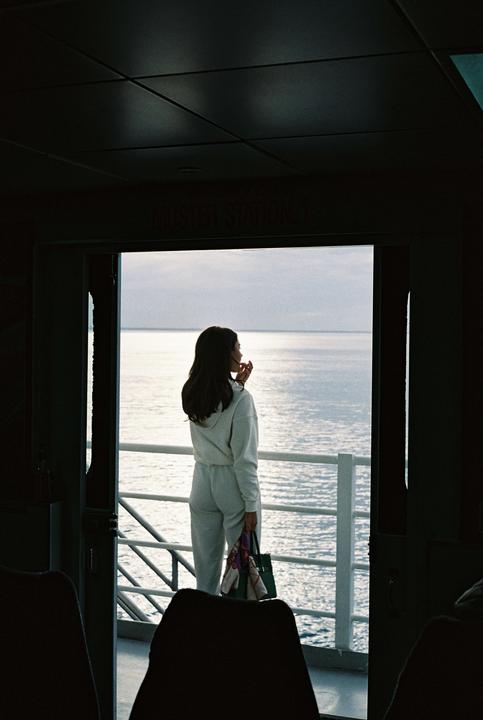 A woman stands on a boat looking out at the ocean.
