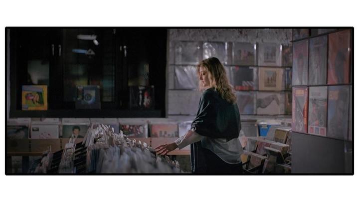 A woman is looking through records in a record store.