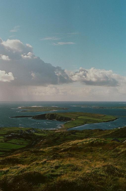 A wide shot shows a body of water with several small islands and green hills in the foreground.