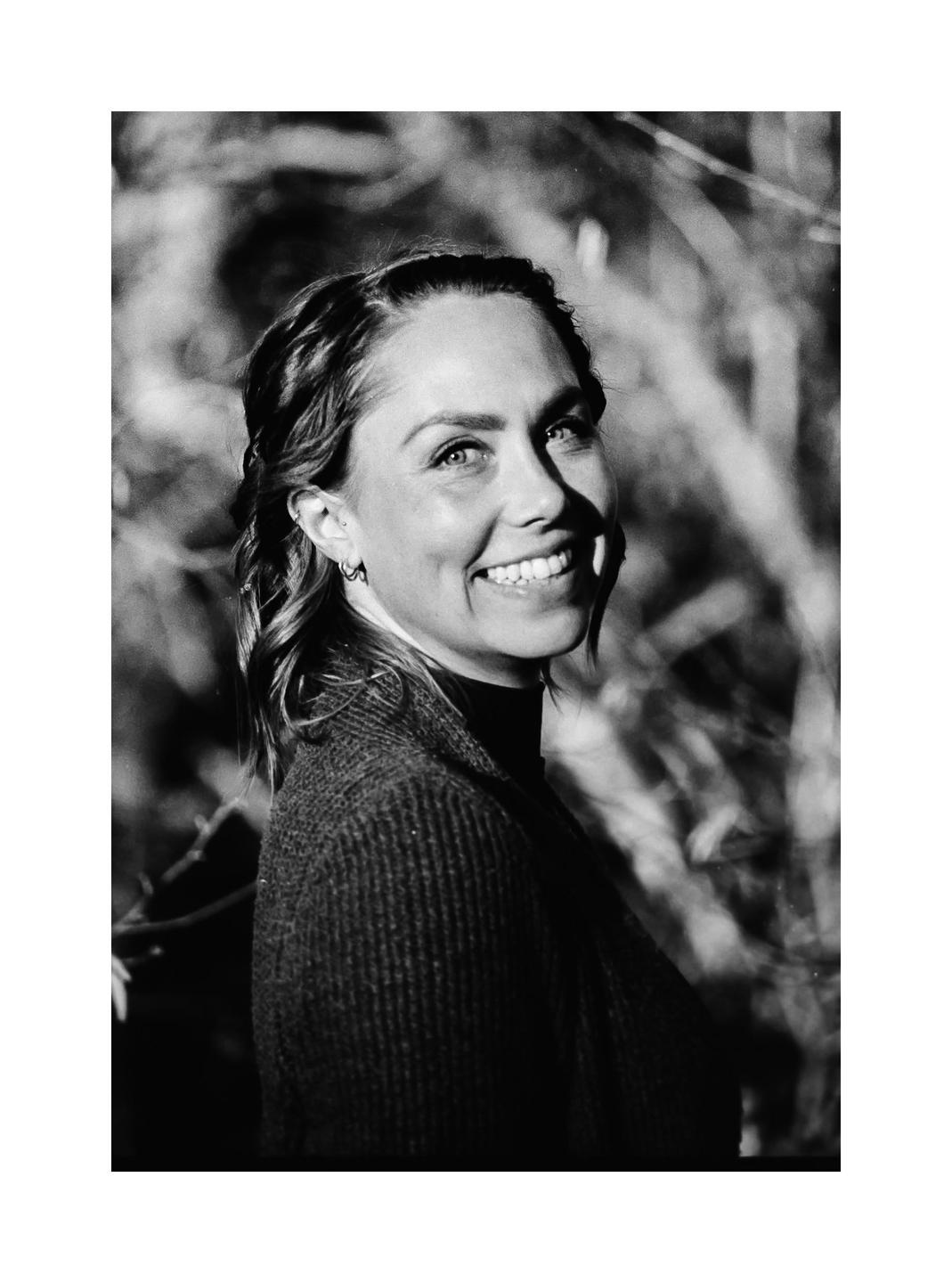 A woman with braided hair smiles while looking up and to the right.