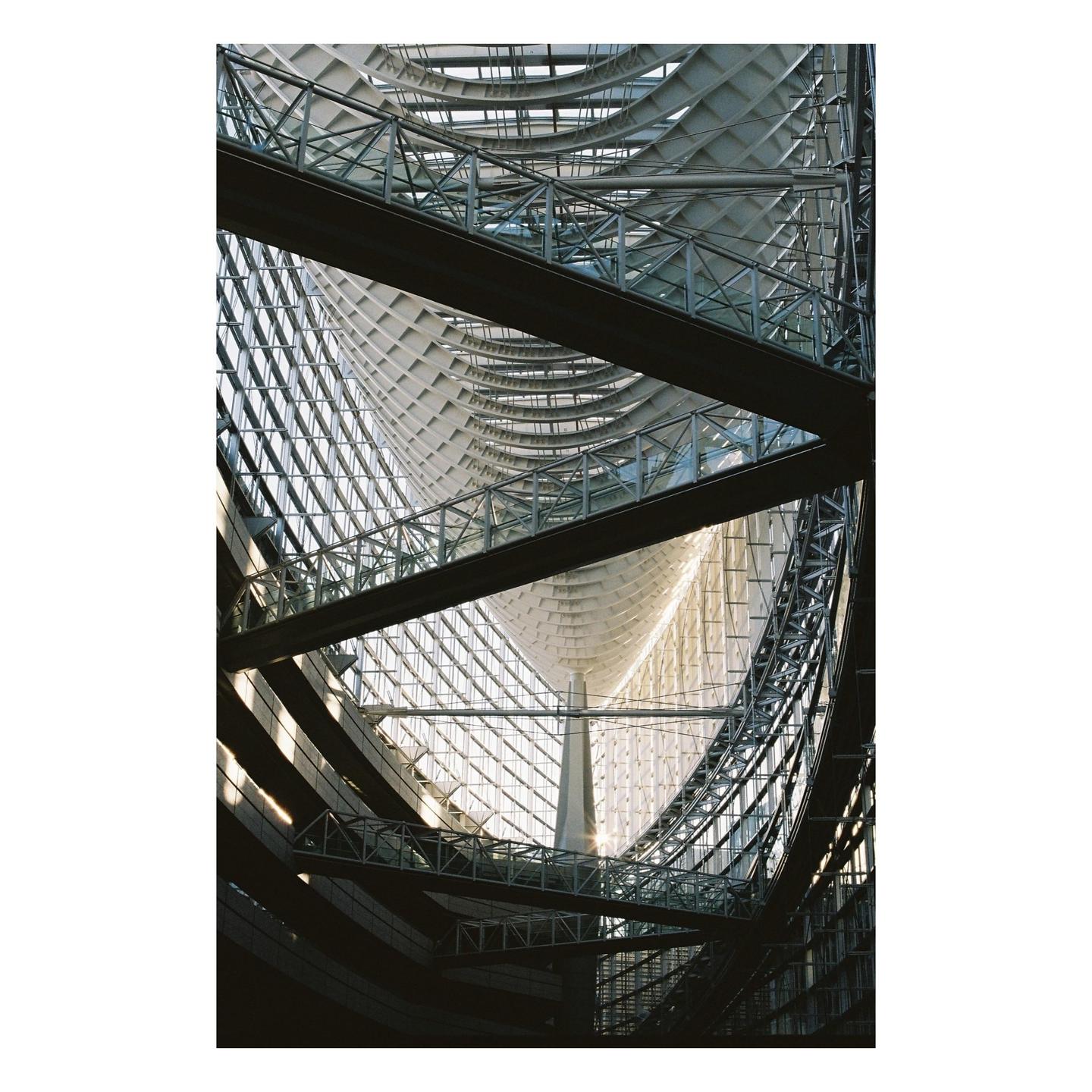 The interior of a modern building features a complex structure of glass, metal beams, and curved white panels.