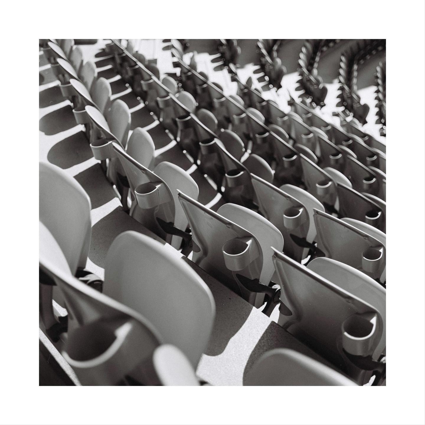 Rows of empty stadium seats are arranged in a diagonal pattern.