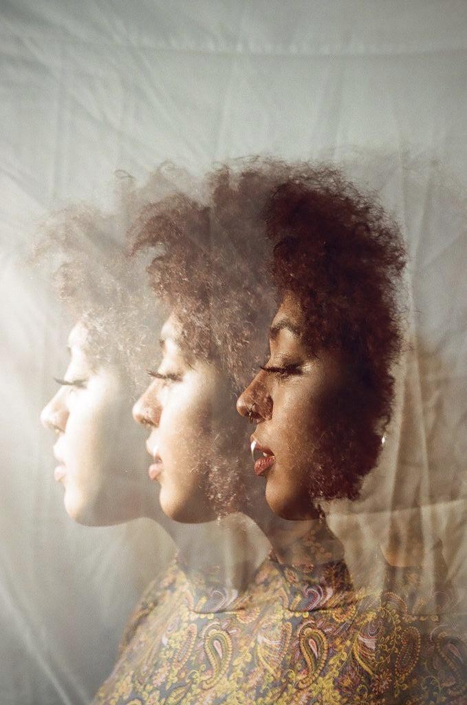 A woman with curly hair is shown in a triple exposure, looking to the left with her eyes closed.