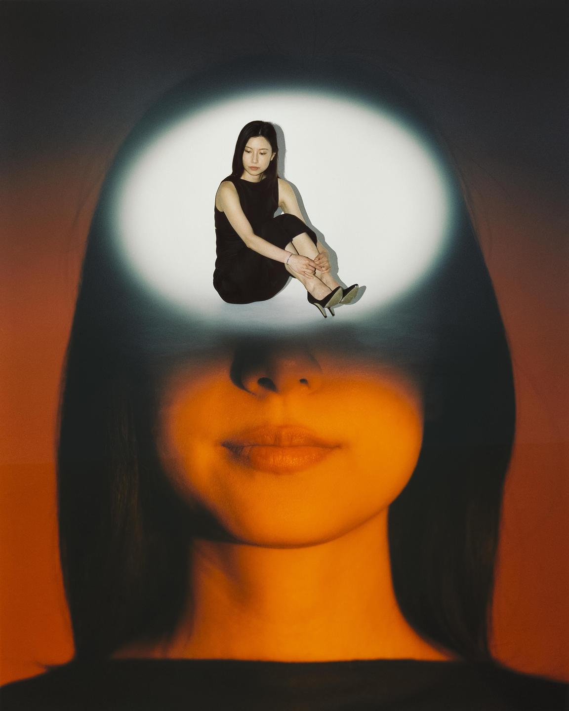 A woman's face is visible with a smaller image of a woman sitting in a spotlight on her forehead.