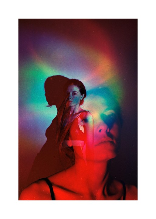 A woman with long hair is shown in a double exposure with colorful light streaks across the frame.