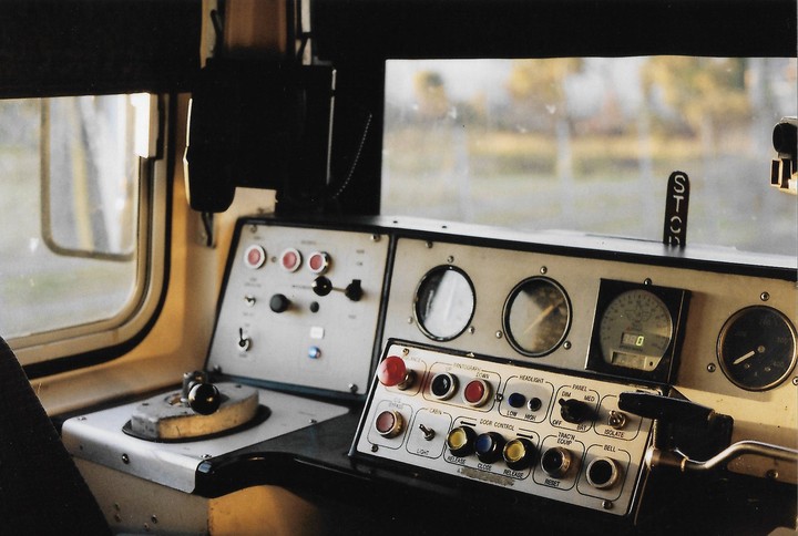 The interior of a train driver's cabin is visible, showing the control panel and gauges.