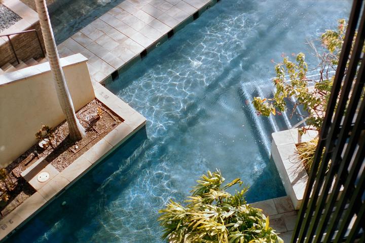 An overhead view shows a swimming pool with steps, surrounded by palm trees and tropical plants.