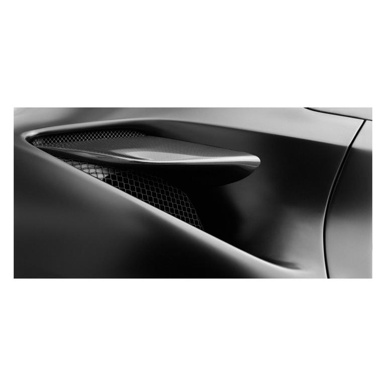 A close-up view shows the air intake and body panel of a car.