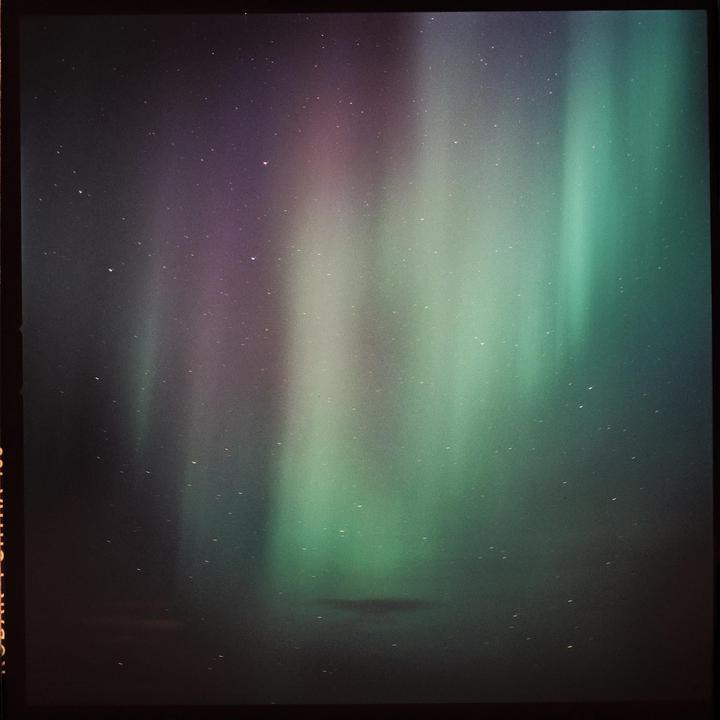 The aurora borealis illuminates the night sky with green and purple light.