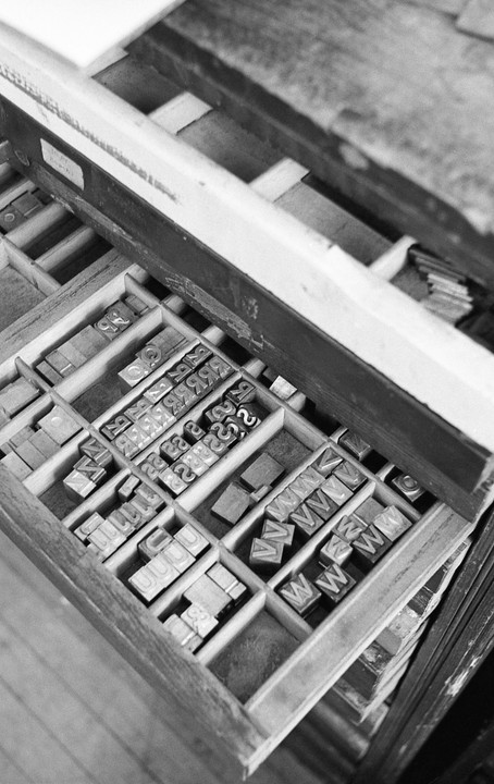 A wooden drawer is filled with metal letterpress type.